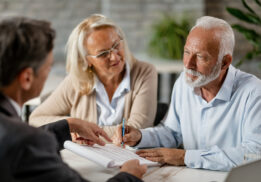 Senior couple signing a contract while having a meeting with ins